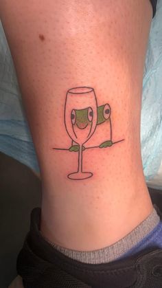 a woman's lower leg with a wine glass tattoo on it