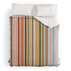 a bed with two pillows on top of it and a striped comforter cover in the middle