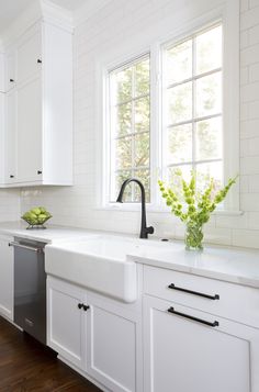 a kitchen with white cabinets and black faucet, sink, dishwasher and window