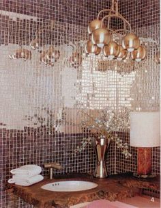 a bathroom sink sitting under a chandelier in front of a mirror covered wall