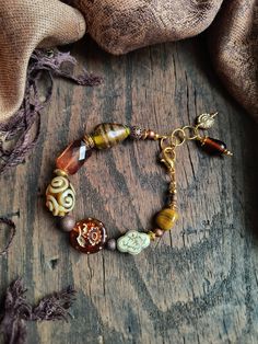 "This bracelet offers an Autumn inspired collection of glass and vintage acrylic beads, with a few antique copper spacers and gold accents to complete the piece. Its length is 7.75\" up to 8.5\" (~20 to 21.5 cm)." Handmade Brown Beaded Bracelets With Czech Glass, Handmade Brown Czech Glass Beaded Bracelets, Handmade Czech Glass Brown Beaded Bracelets, Brown Copper Bracelets With Round Beads, Bohemian Brown Beaded Copper Bracelets, Bohemian Brown Copper Beaded Bracelets, Brown Czech Glass Bracelets With Colorful Beads, Brown Czech Glass Bracelet With Colorful Beads, Brown Copper Beaded Bracelets With Round Beads