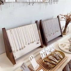 jewelry is displayed on display in a store with white walls and wooden trays filled with necklaces