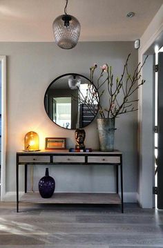 a room with a table, mirror and vase on it