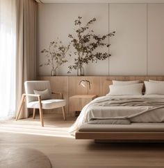 a large bed sitting in a bedroom next to a white chair and wooden flooring