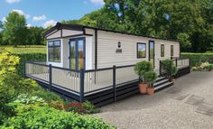 a mobile home is shown in the middle of a garden with potted plants and trees