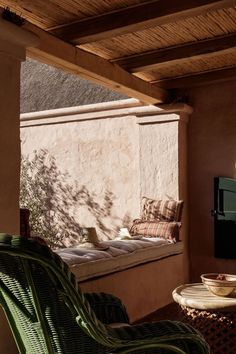 a patio with a table and chairs under a wooden roof next to a wall that has a window on it