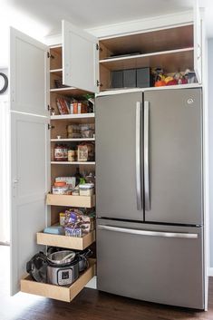 an organized kitchen with stainless steel refrigerator and pull out pantry drawers