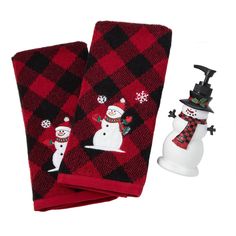 two red and black towels with snowmen on them next to a white snowman