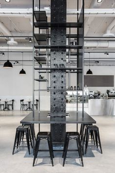 an industrial style dining room with black tables and stools in front of the table