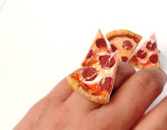 a person's hand holding two slices of pizza in their fingers, with the other half eaten