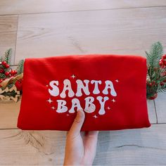 someone is holding up a red santa baby bag with white letters and stars on it