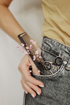 a woman holding a pair of scissors and comb in her pocket with pink flowers on it