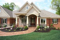 a large brick house with lots of windows and landscaping on the front lawn, surrounded by green grass