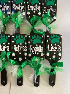 green and black personalized pet id holders with bows on them, hanging from the wall