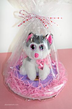 a stuffed animal in a plastic bag on top of a pink surface with some grass