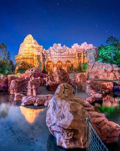 an amusement park at night with rocks and water