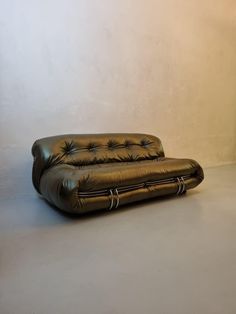 a brown leather couch sitting on top of a white floor next to a wall with a lamp