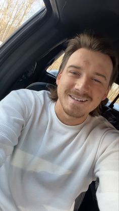 a man sitting in the driver's seat of a car looking at the camera