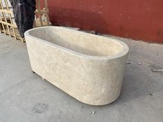 a bathtub sitting on the ground next to a building with a red wall behind it