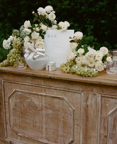 a table topped with white flowers and greenery next to a sign that reads bar