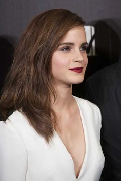 a woman with long brown hair wearing a white dress and red lipstick at an event