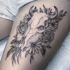 a woman's thigh with a bull skull and flowers on it