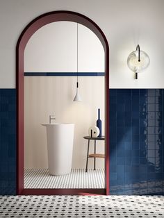 a bathroom with blue and white tiles, an arch shaped sink and two lamps hanging from the ceiling