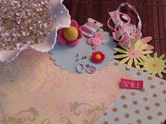 a table topped with lots of assorted items on top of a wooden floor next to a vase filled with flowers