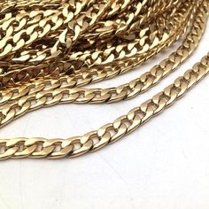 several gold chains on a white surface