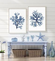 two blue and white paintings on the wall above a table with seaweed in baskets