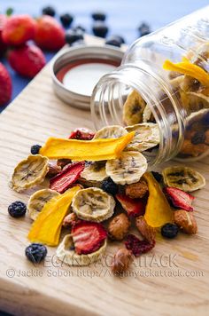 a jar filled with fruit and nuts next to some strawberries on a cutting board