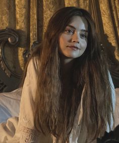 a woman with long hair sitting on a bed