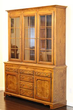 a wooden china cabinet sitting on top of a hard wood floor