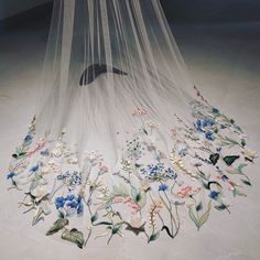 a white veil with flowers and butterflies on the bottom is hanging from it's side