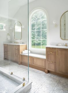 a large bathroom with two sinks and a bathtub in front of a big window