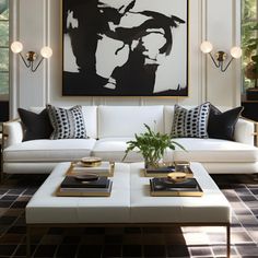 a living room with white couches and black and white artwork