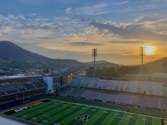 the sun is setting over an empty football field