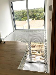 an open window in a room with wooden flooring and metal bars on the sides