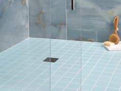 a blue tiled bathroom with a wooden brush on the floor and a tile shower stall