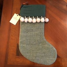 a green stocking with white pom - poms hanging from it's side