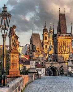 an old city with many buildings and statues on the side walk near a street light