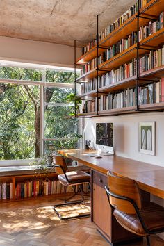 a home office with bookshelves, desk and chair in front of large window