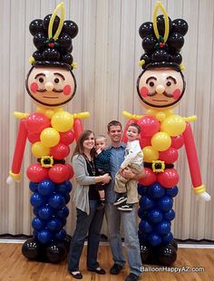 a family poses in front of balloon art depicting two people dressed as mickey and minnie mouse