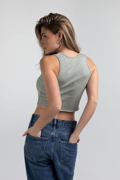 a woman with her back to the camera, wearing jeans and a cropped tank top