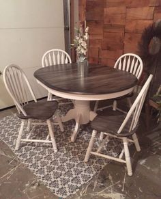 a table with four chairs around it on a rug in front of a brick wall