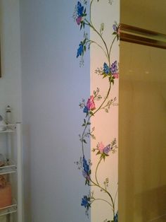 the wall is painted with flowers and vines on it, along with a shower curtain