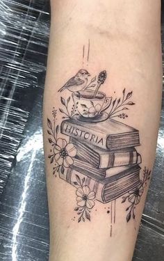 a tattoo on the leg of a woman with books and flowers