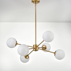 a brass chandelier with five white glass balls