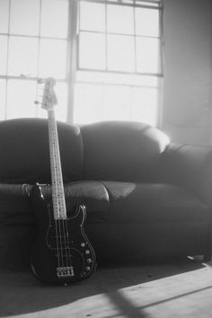 an electric guitar laying on the floor next to a couch in front of a window