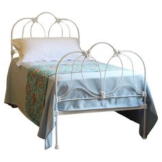 a white metal bed with blue sheets and pillows on top of the headboard, in front of a white background